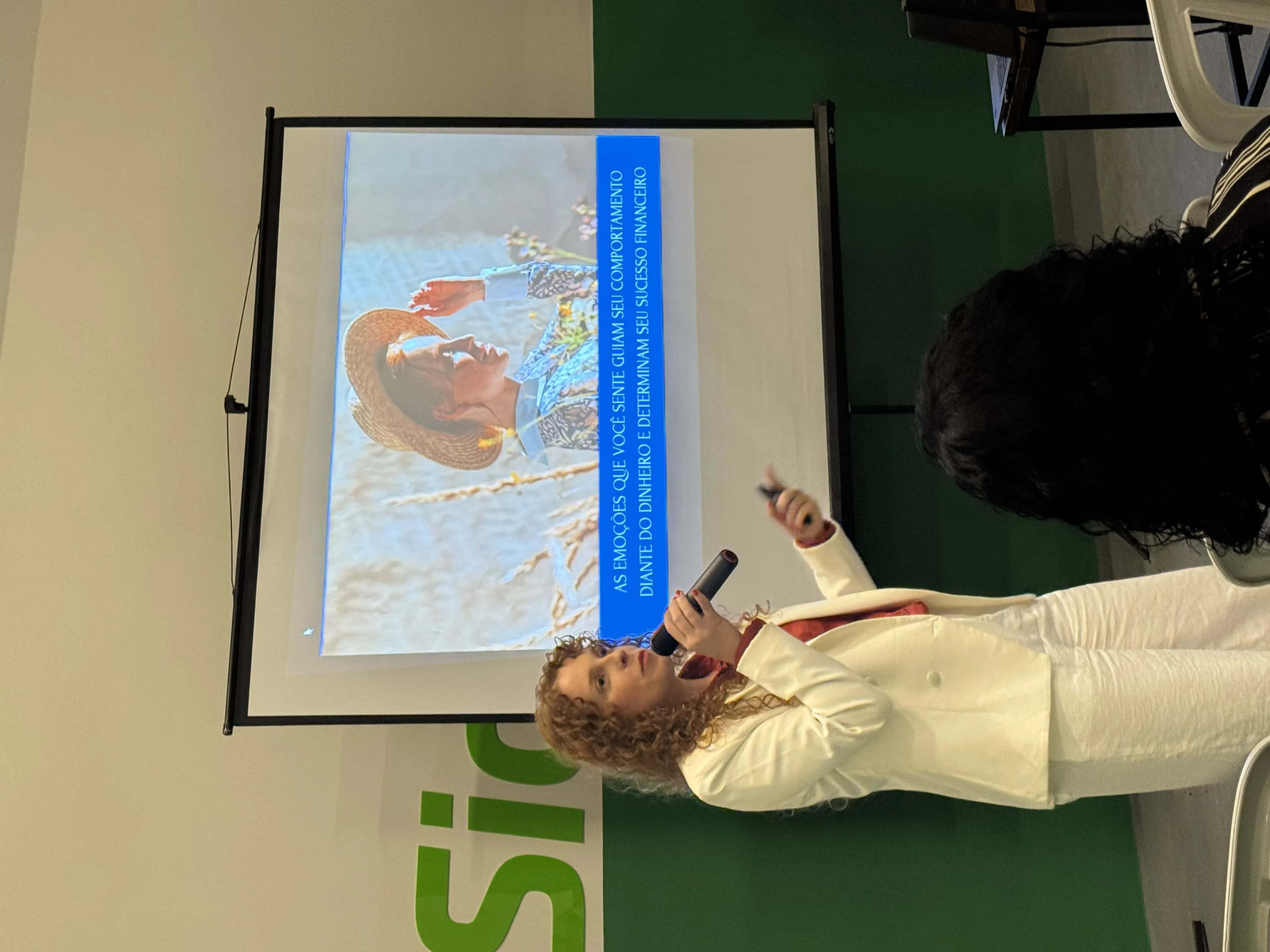 Aline da Costa Lourenço falando ao microfone durante palestra